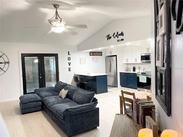 living room with ceiling fan, french doors, a textured ceiling, lofted ceiling, and light wood-type flooring