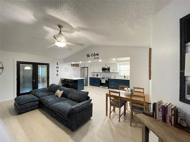 living room featuring ceiling fan, sink, french doors, a textured ceiling, and vaulted ceiling