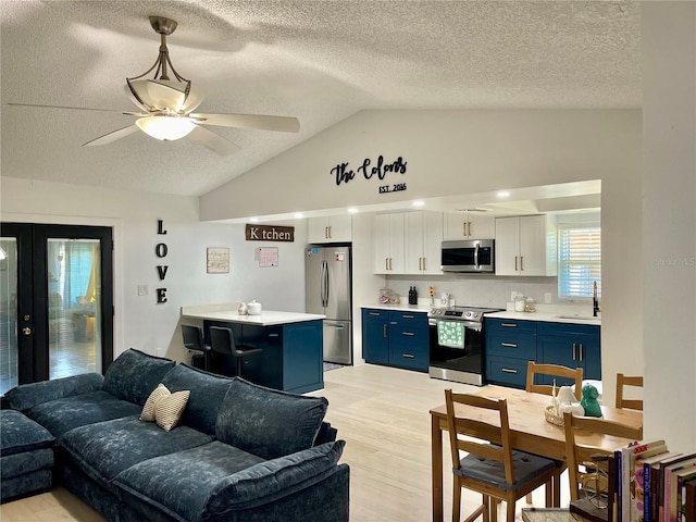 kitchen featuring light wood-type flooring, stainless steel appliances, blue cabinets, white cabinets, and lofted ceiling