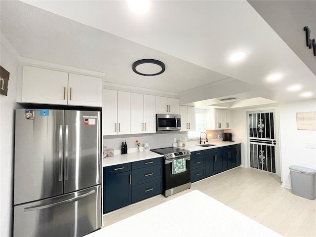 kitchen featuring white cabinets, blue cabinets, sink, light wood-type flooring, and stainless steel appliances