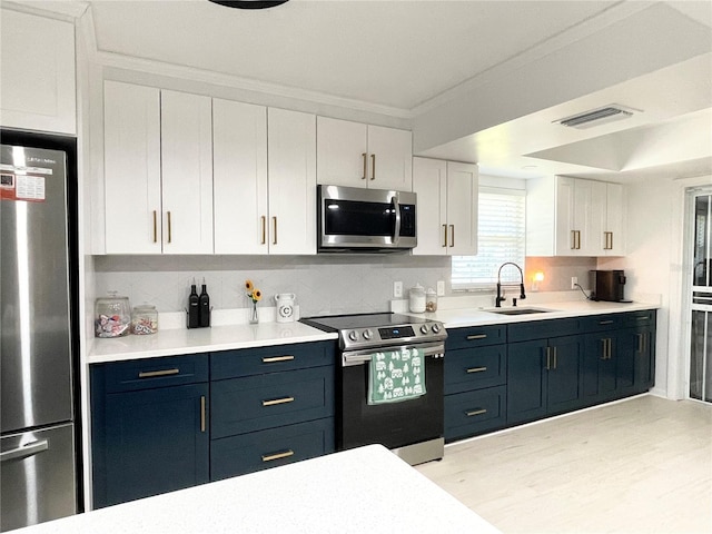 kitchen featuring blue cabinetry, white cabinetry, sink, appliances with stainless steel finishes, and ornamental molding