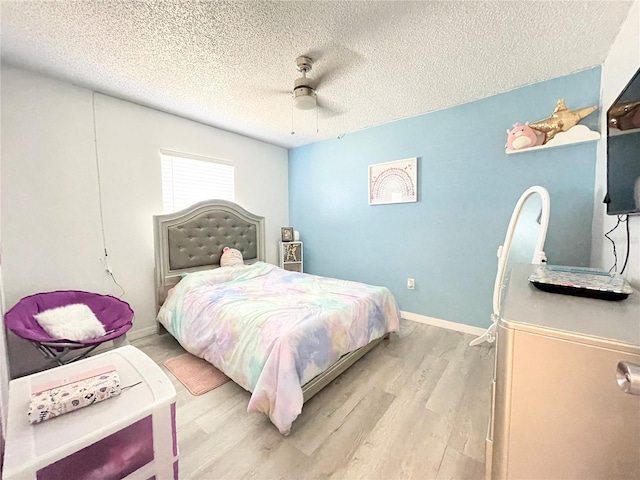 bedroom with ceiling fan, light hardwood / wood-style flooring, and a textured ceiling