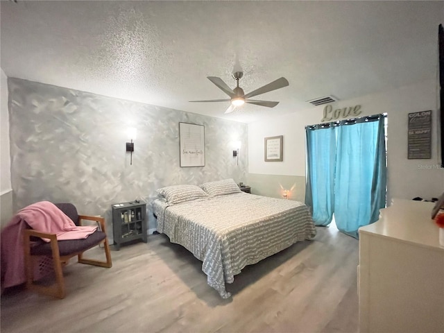 bedroom with hardwood / wood-style floors, a textured ceiling, and ceiling fan