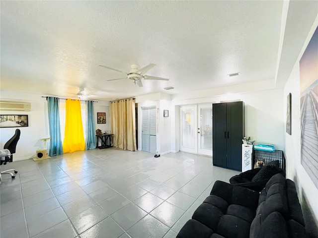 living room featuring ceiling fan, an AC wall unit, a textured ceiling, and light tile patterned floors