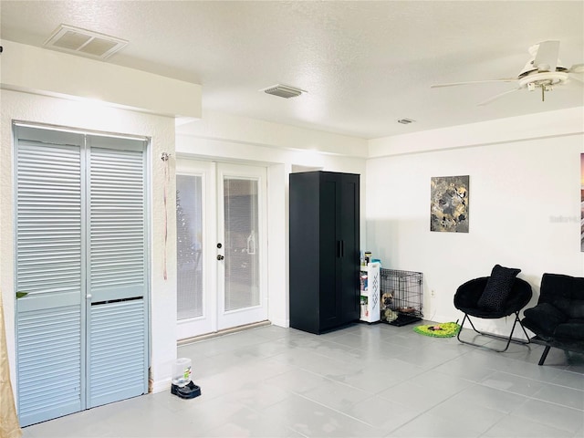 living area with ceiling fan, light tile patterned floors, a textured ceiling, and french doors