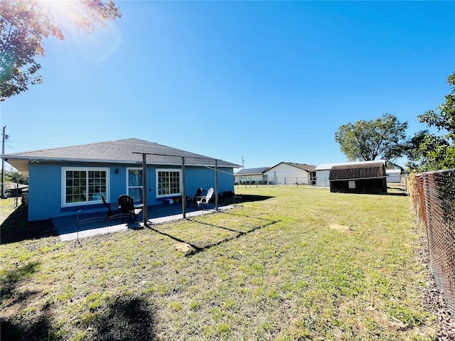 rear view of house with a lawn, a storage unit, and a patio area