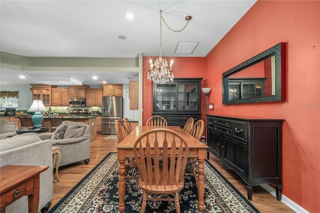 dining space with light hardwood / wood-style floors and an inviting chandelier