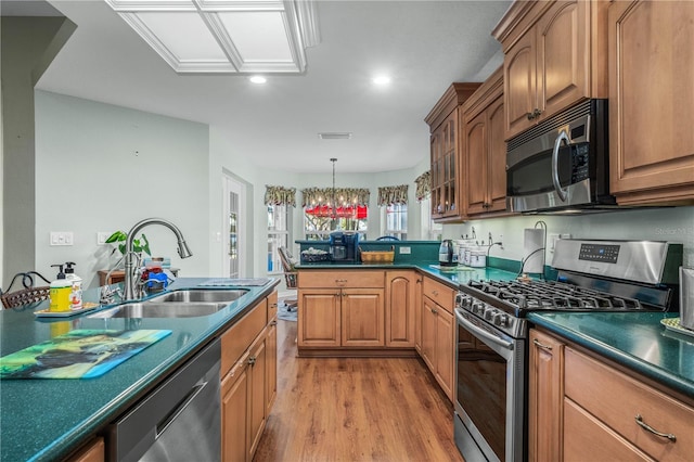 kitchen featuring sink, decorative light fixtures, light hardwood / wood-style flooring, a notable chandelier, and stainless steel appliances