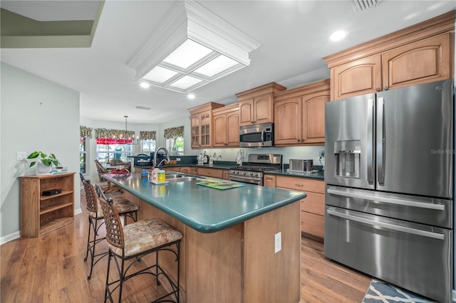 kitchen with a breakfast bar, a kitchen island with sink, sink, light hardwood / wood-style flooring, and appliances with stainless steel finishes