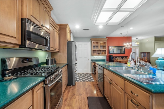 kitchen featuring sink, stainless steel appliances, an inviting chandelier, light hardwood / wood-style flooring, and pendant lighting