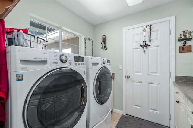 clothes washing area featuring washing machine and dryer, light tile patterned flooring, and cabinets