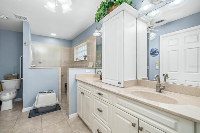 bathroom with a tile shower, tile patterned flooring, vanity, and toilet