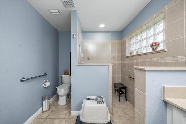 bathroom with a tile shower, tile patterned floors, vanity, and toilet