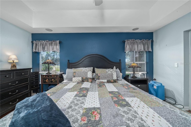 bedroom with wood-type flooring and a raised ceiling