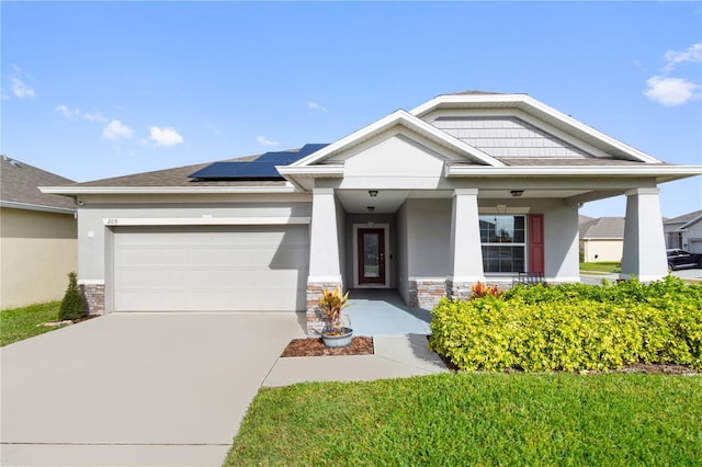 view of front of house featuring covered porch, solar panels, and a garage