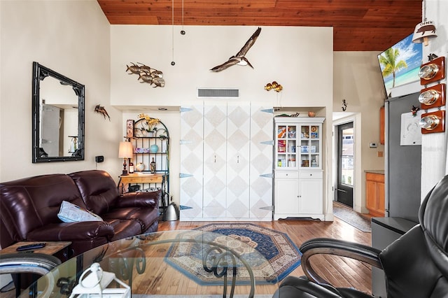 living room featuring hardwood / wood-style flooring, a towering ceiling, tile walls, and wooden ceiling