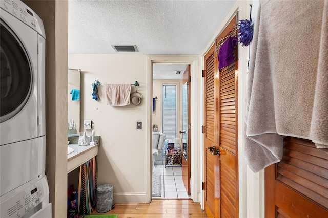 interior space featuring stacked washer / dryer, a textured ceiling, and light wood-type flooring