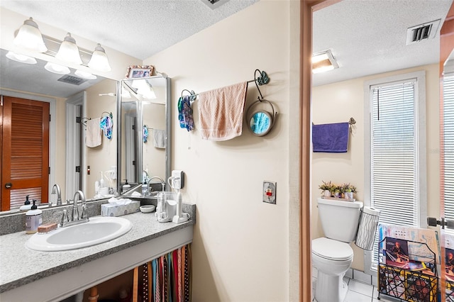 bathroom featuring tile patterned flooring, vanity, a textured ceiling, and toilet