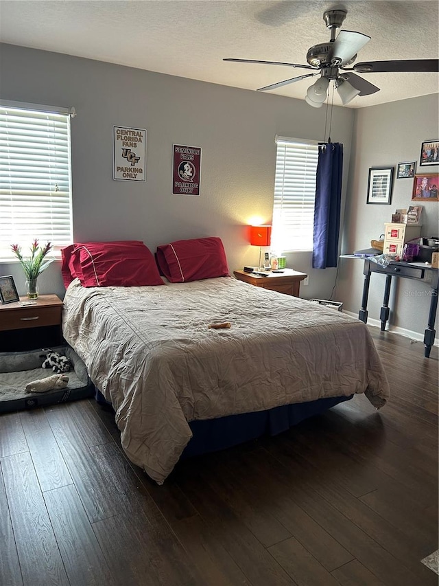 bedroom with ceiling fan, dark hardwood / wood-style flooring, a textured ceiling, and multiple windows