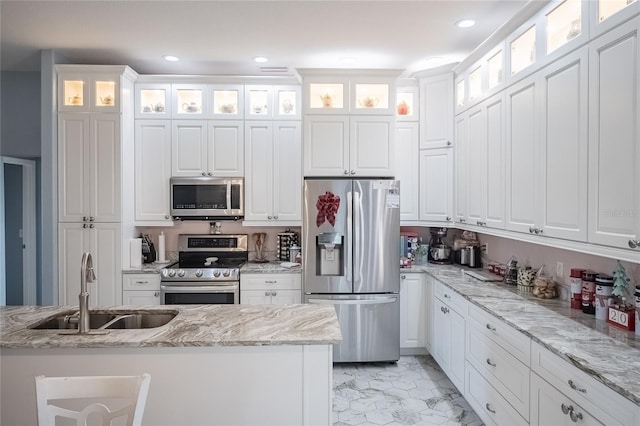 kitchen featuring light stone countertops, appliances with stainless steel finishes, white cabinetry, and sink