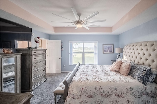 carpeted bedroom featuring a raised ceiling and ceiling fan