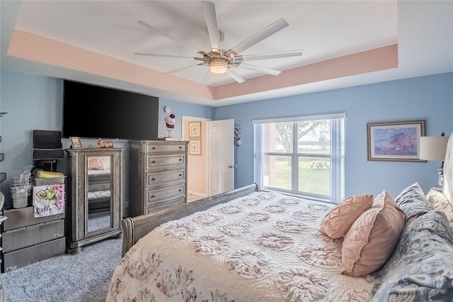 bedroom with a tray ceiling, ceiling fan, and carpet floors