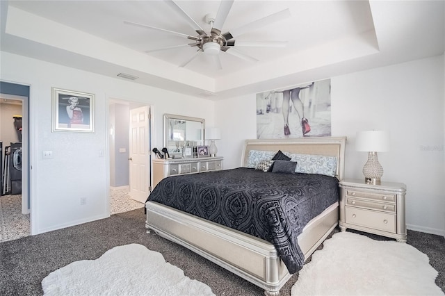 bedroom with a tray ceiling, ceiling fan, and dark carpet