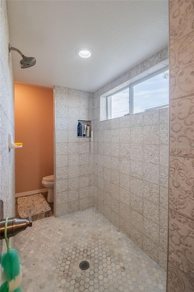 bathroom with a tile shower and toilet