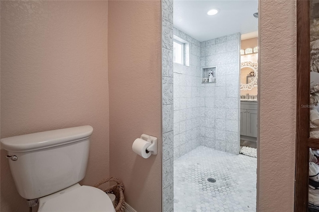 bathroom featuring vanity, toilet, and a tile shower