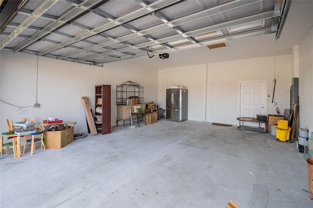 garage featuring stainless steel fridge and a garage door opener