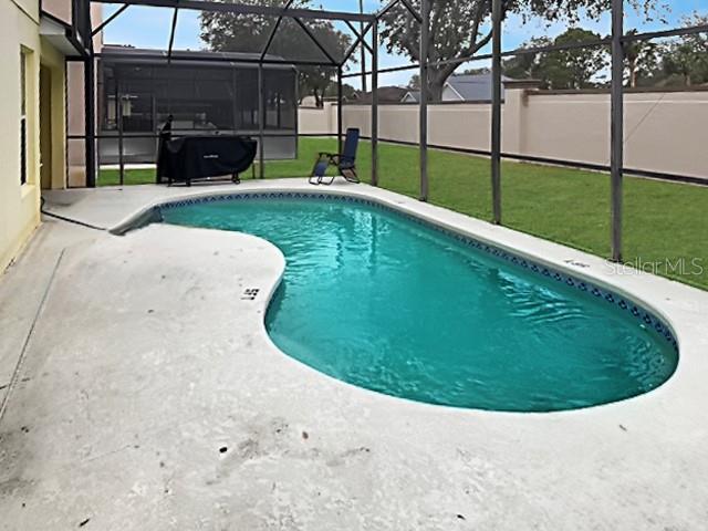 view of swimming pool with a lawn, a patio area, and a lanai