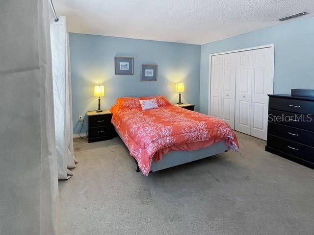 bedroom with a closet, light colored carpet, and a textured ceiling