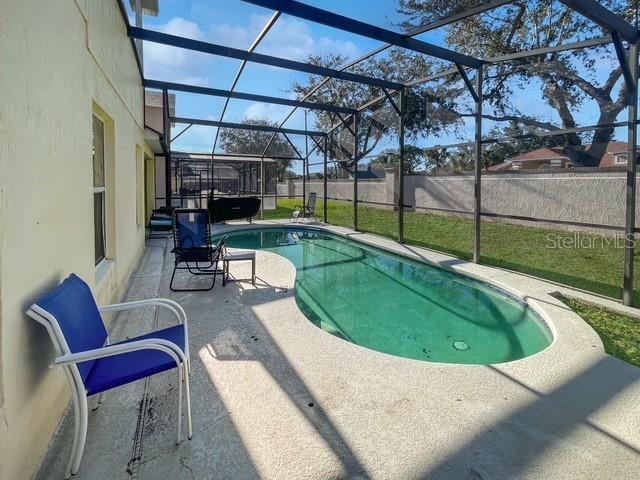 view of swimming pool featuring a lanai, a patio area, and a yard