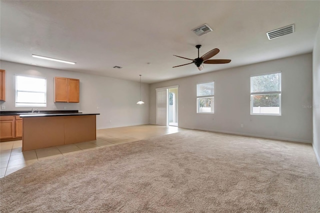 unfurnished living room with ceiling fan, sink, and light colored carpet