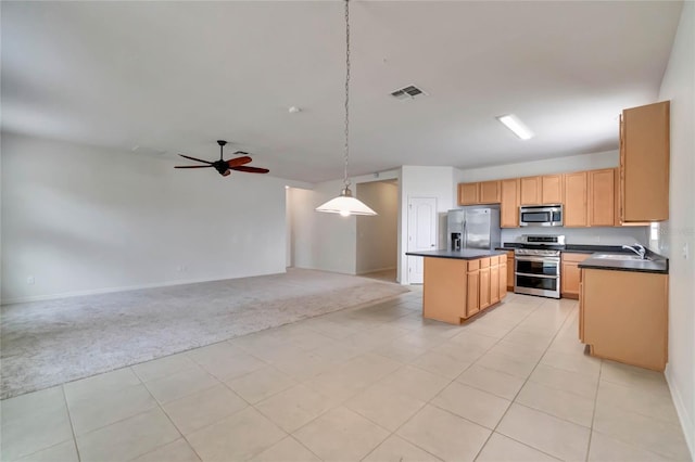 kitchen with hanging light fixtures, ceiling fan, appliances with stainless steel finishes, a kitchen island, and light colored carpet