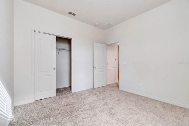 unfurnished bedroom featuring light carpet and a closet