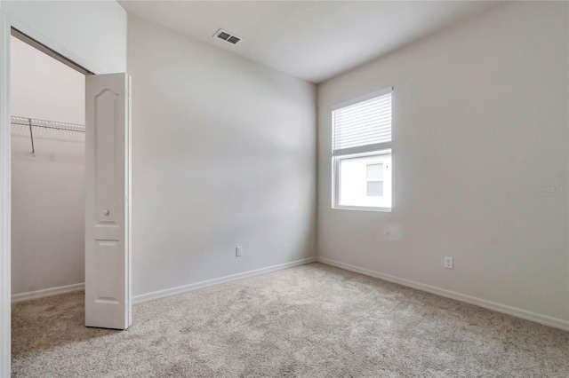 unfurnished bedroom with a closet and light colored carpet