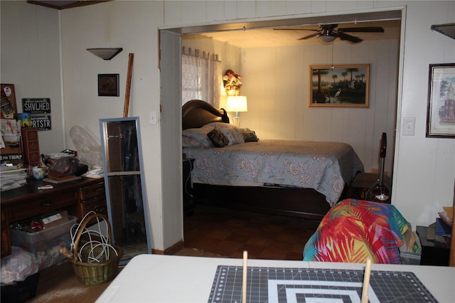 bedroom with ceiling fan and wood walls