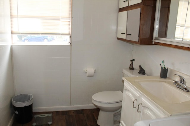 bathroom with wood-type flooring, a healthy amount of sunlight, vanity, and toilet