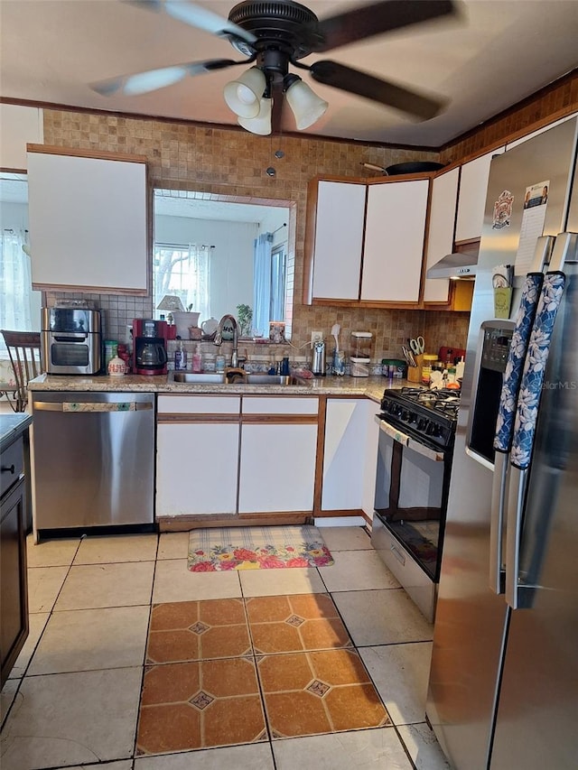 kitchen with extractor fan, light tile patterned flooring, white cabinets, stainless steel appliances, and a sink