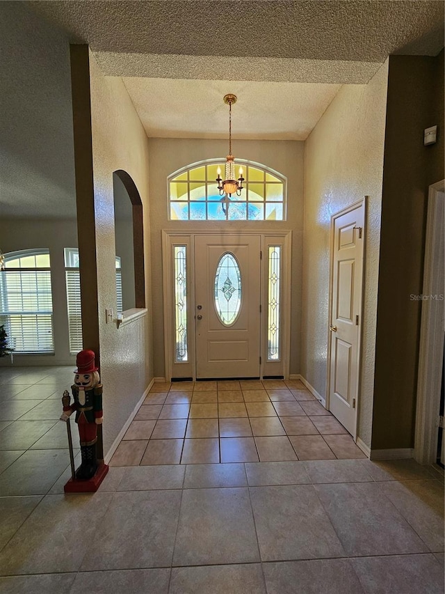 1072 Old Cutler Rd, Lake Wales, FL 33898 - tiled entryway featuring a textured ceiling, plenty of natural light, a chandelier, a textured wall, and arched walkways