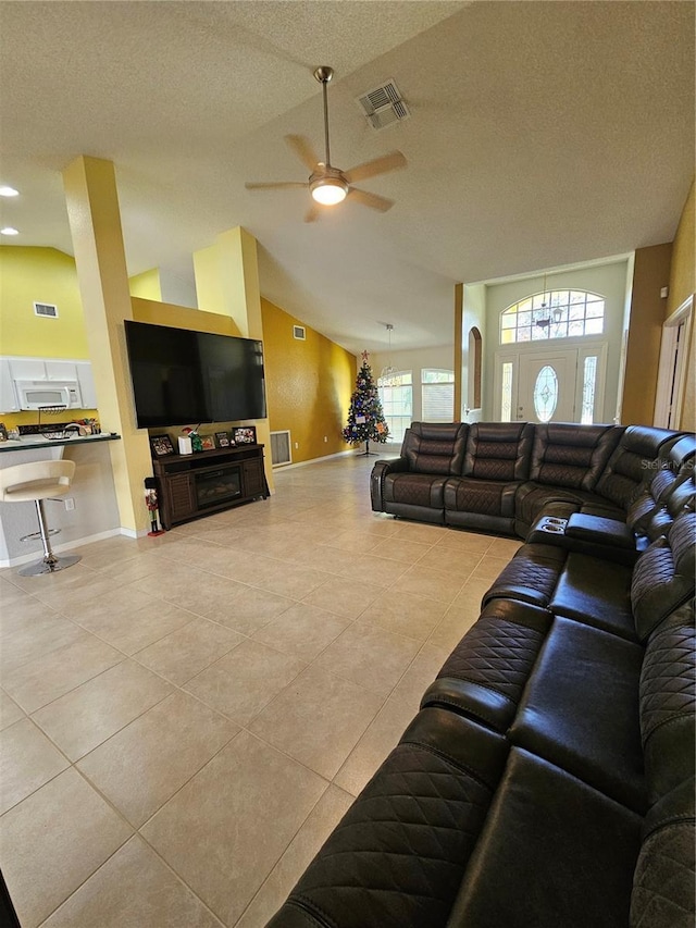 living room featuring ceiling fan, light tile patterned flooring, a textured ceiling, and high vaulted ceiling