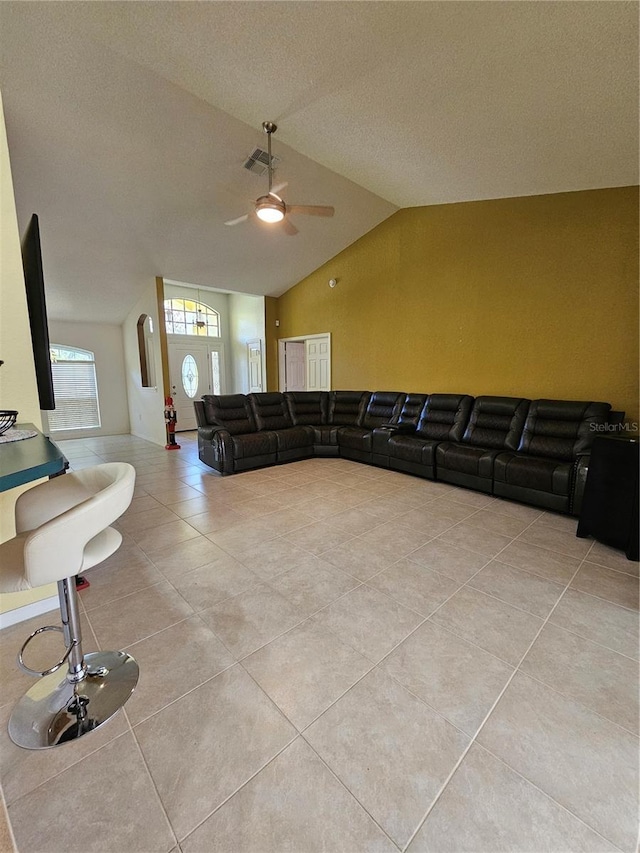 living room with light tile patterned floors, a textured ceiling, ceiling fan, and lofted ceiling