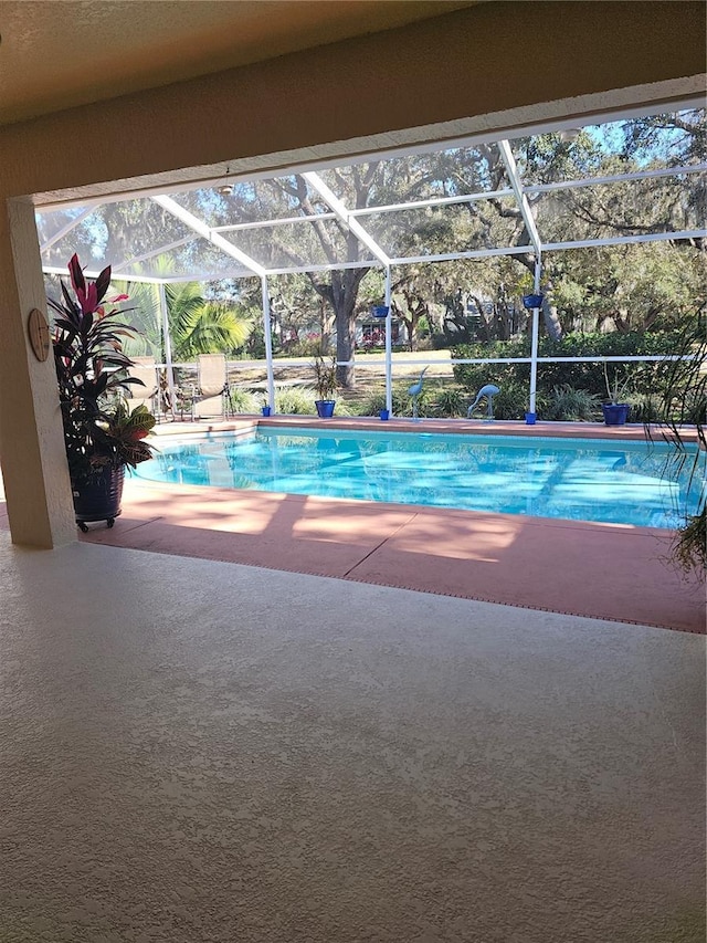 view of swimming pool featuring a patio and glass enclosure