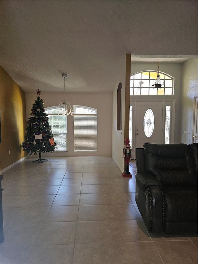 foyer entrance with tile patterned floors, a wealth of natural light, a textured ceiling, and a notable chandelier