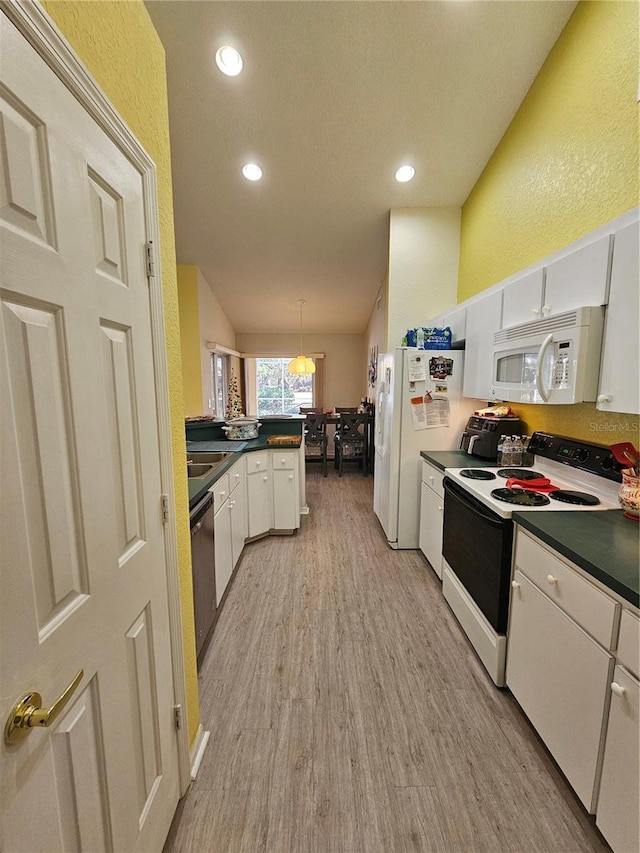 kitchen featuring kitchen peninsula, white appliances, decorative light fixtures, light hardwood / wood-style flooring, and white cabinetry