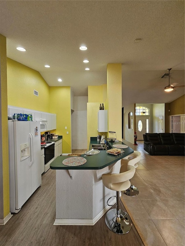 1072 Old Cutler Rd, Lake Wales, FL 33898 - kitchen with white appliances, a breakfast bar, a peninsula, white cabinetry, and a textured ceiling