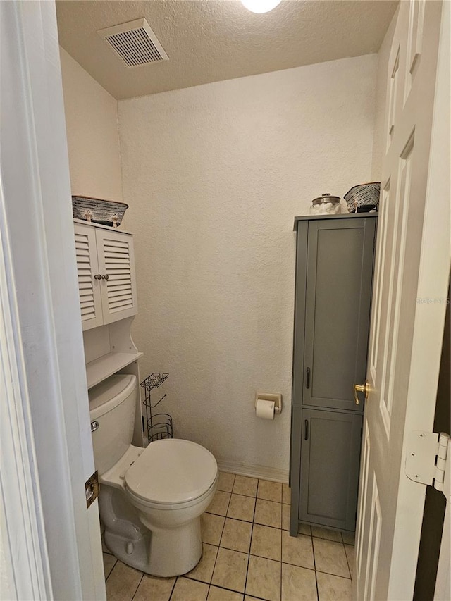 bathroom with tile patterned floors, toilet, and a textured ceiling