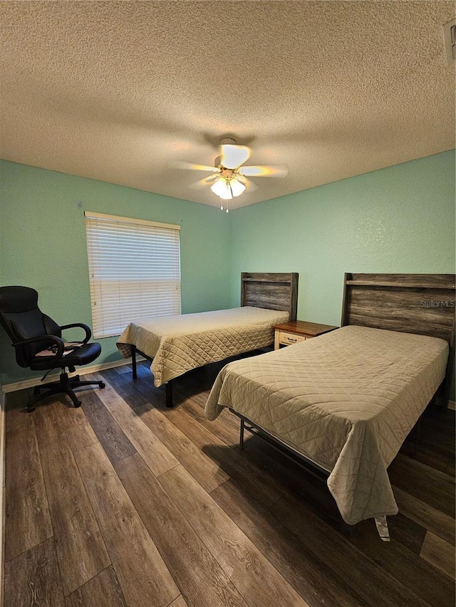 bedroom with ceiling fan, wood-type flooring, and a textured ceiling