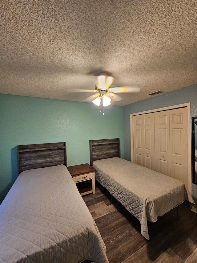 bedroom featuring dark hardwood / wood-style flooring, a textured ceiling, a closet, and ceiling fan